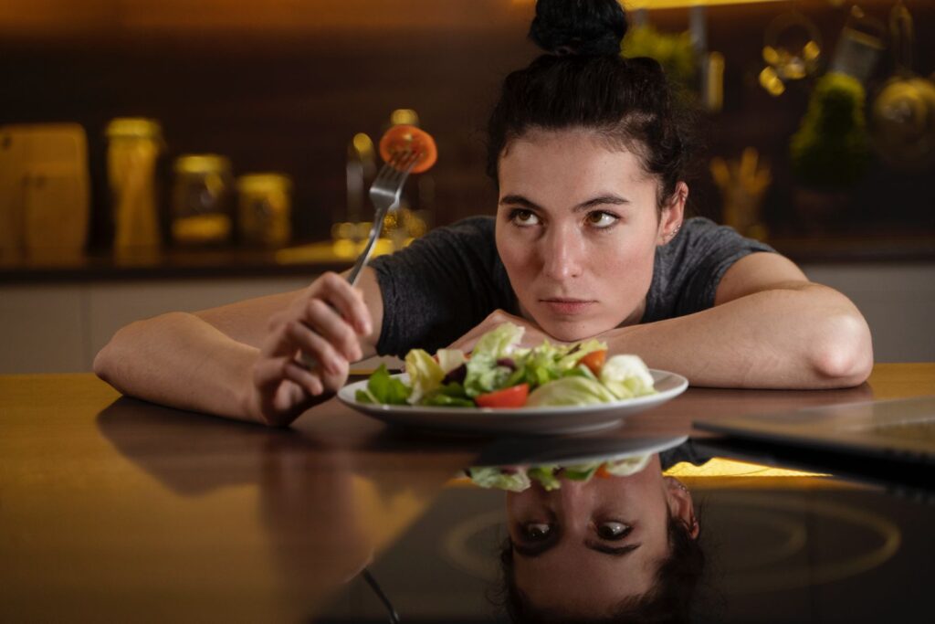 Mujer sentada en una mesa delante de un plato lleno de ensalada
